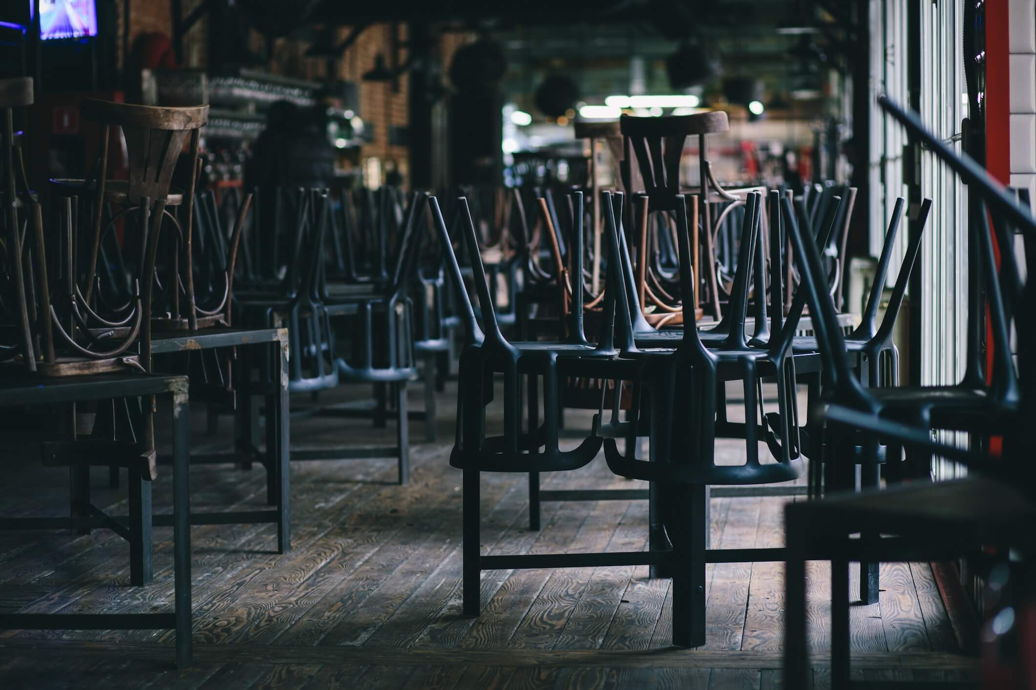 Empty bar with chairs stacked on tables, a business open but getting no foot traffic without proper distribution.