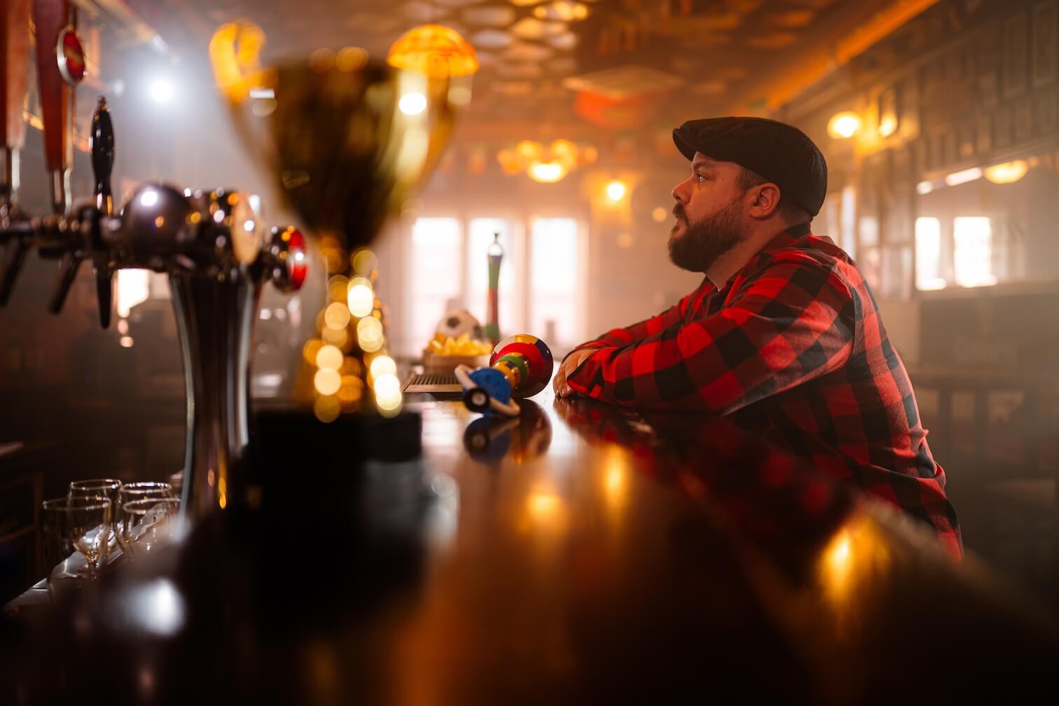 A man sitting alone at a bar, representing the isolation of brands posting into an empty social media feed.
