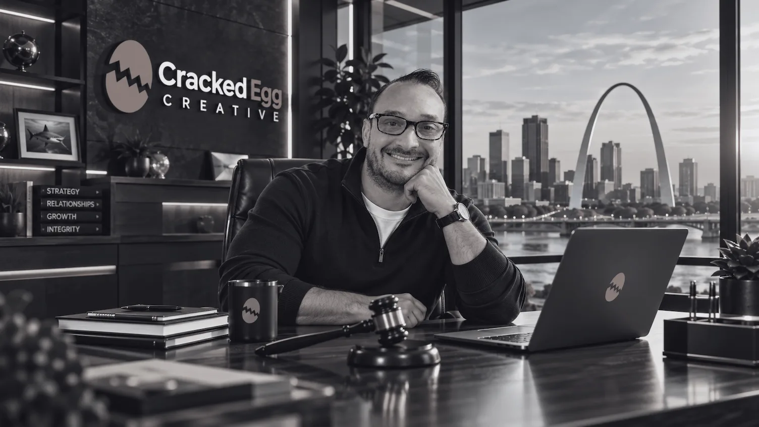 Tom Leto, Chief of Strategic Development at Cracked Egg Creative, at his desk with a judge's gavel and the St. Louis Arch behind him